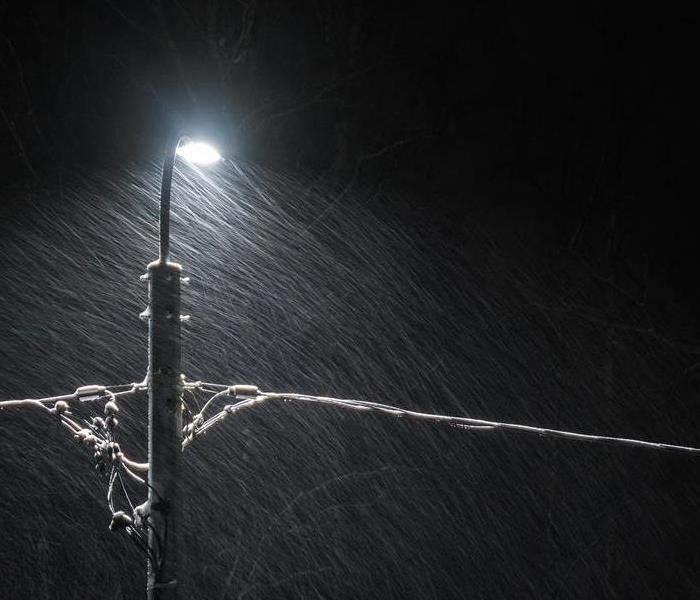 rain and snow on a dark night hitting a street lamp